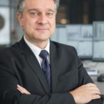 Corporate professional with arms crossed in modern office, symbolizing leadership and confidence.